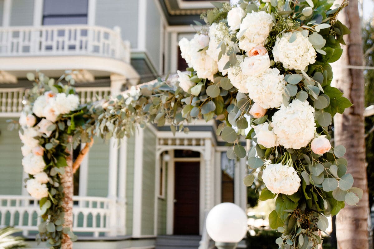 Floral decorations with white and peach flowers adorn the entrance of a vintage green house with balconies at Heritage Square, Oxnard.