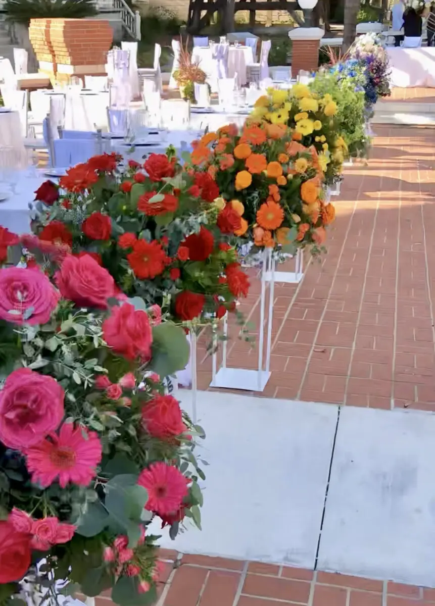 Outdoor wedding reception table at Heritage Square, Oxnard, decorated with a vibrant array of colorful flowers along a pathway.