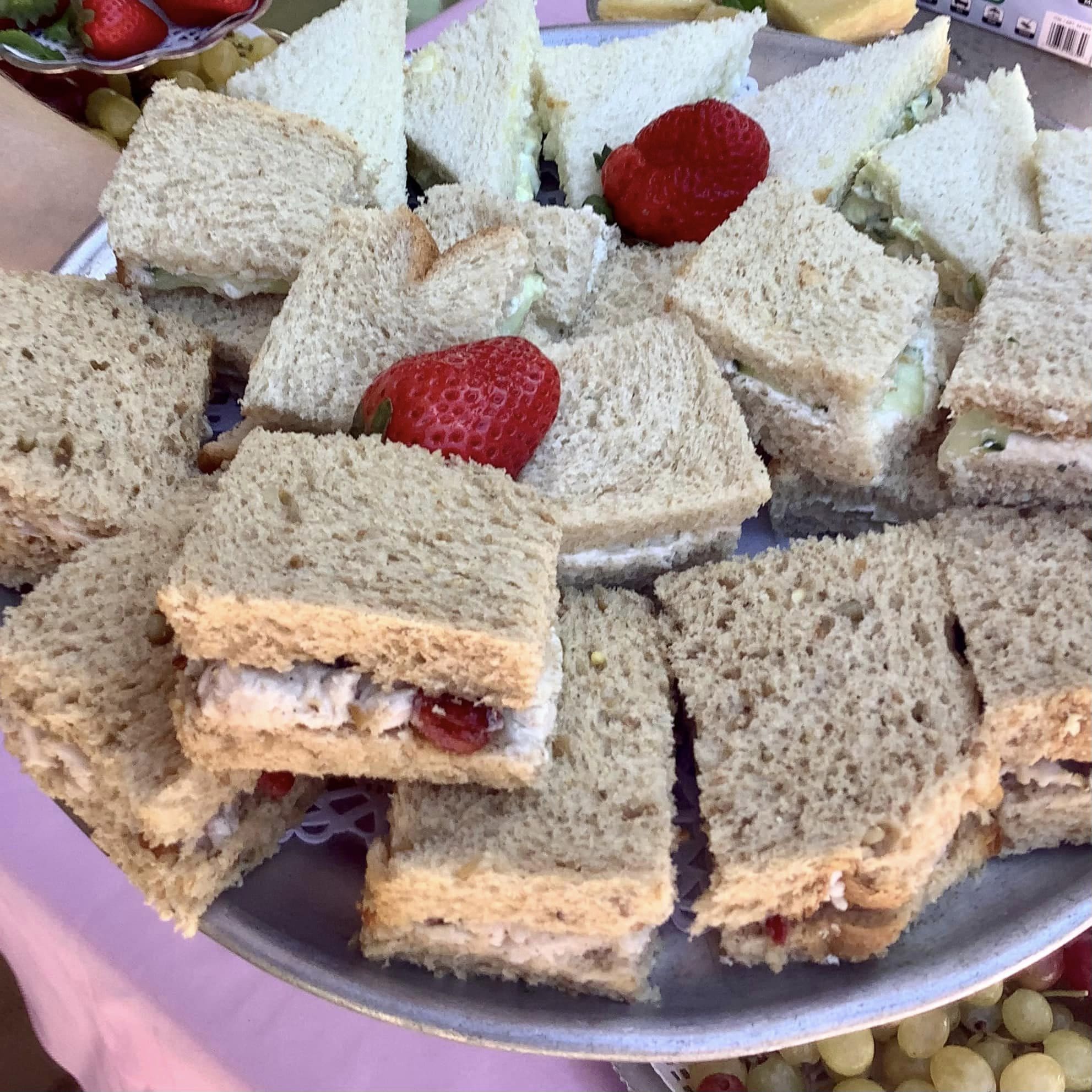 A plate of assorted sandwiches, some made with white bread and others with whole wheat, garnished with strawberries.
