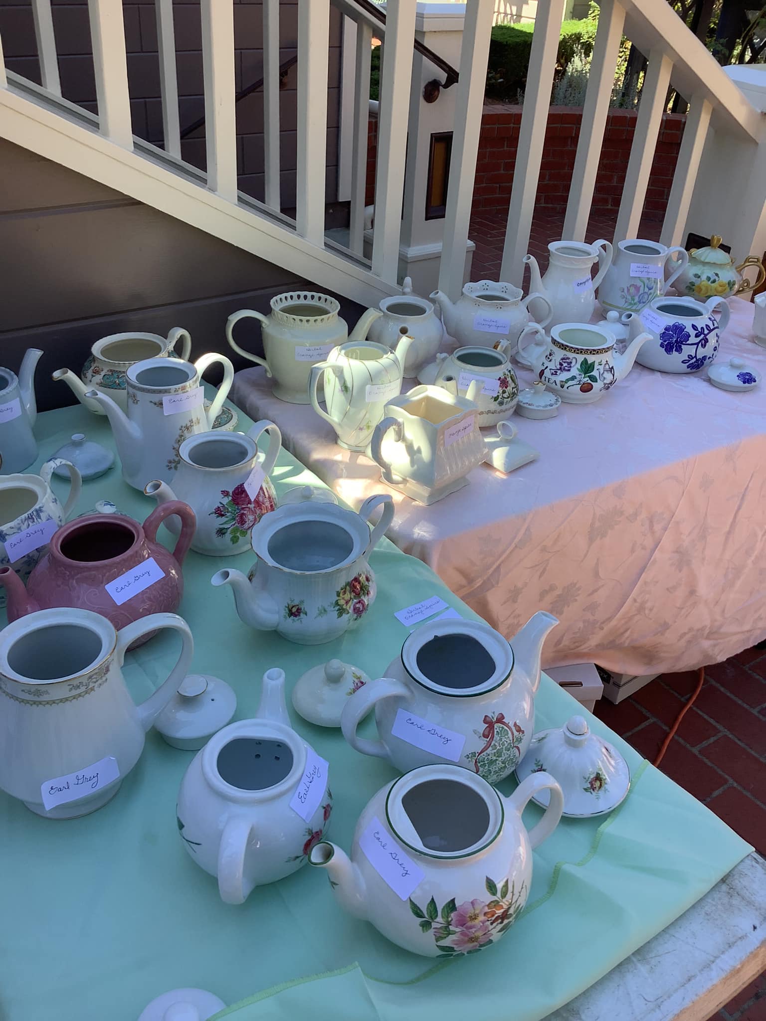 Various teapots displayed on a table for sale at an outdoor market in Heritage Square, Oxnard, with price tags visible.