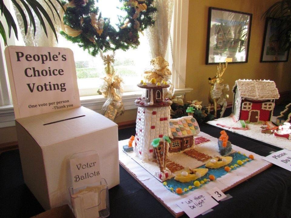 A display of gingerbread houses at Oxnard's Heritage Square, with a "people's choice voting" ballot box; festive decorations visible in the background.
