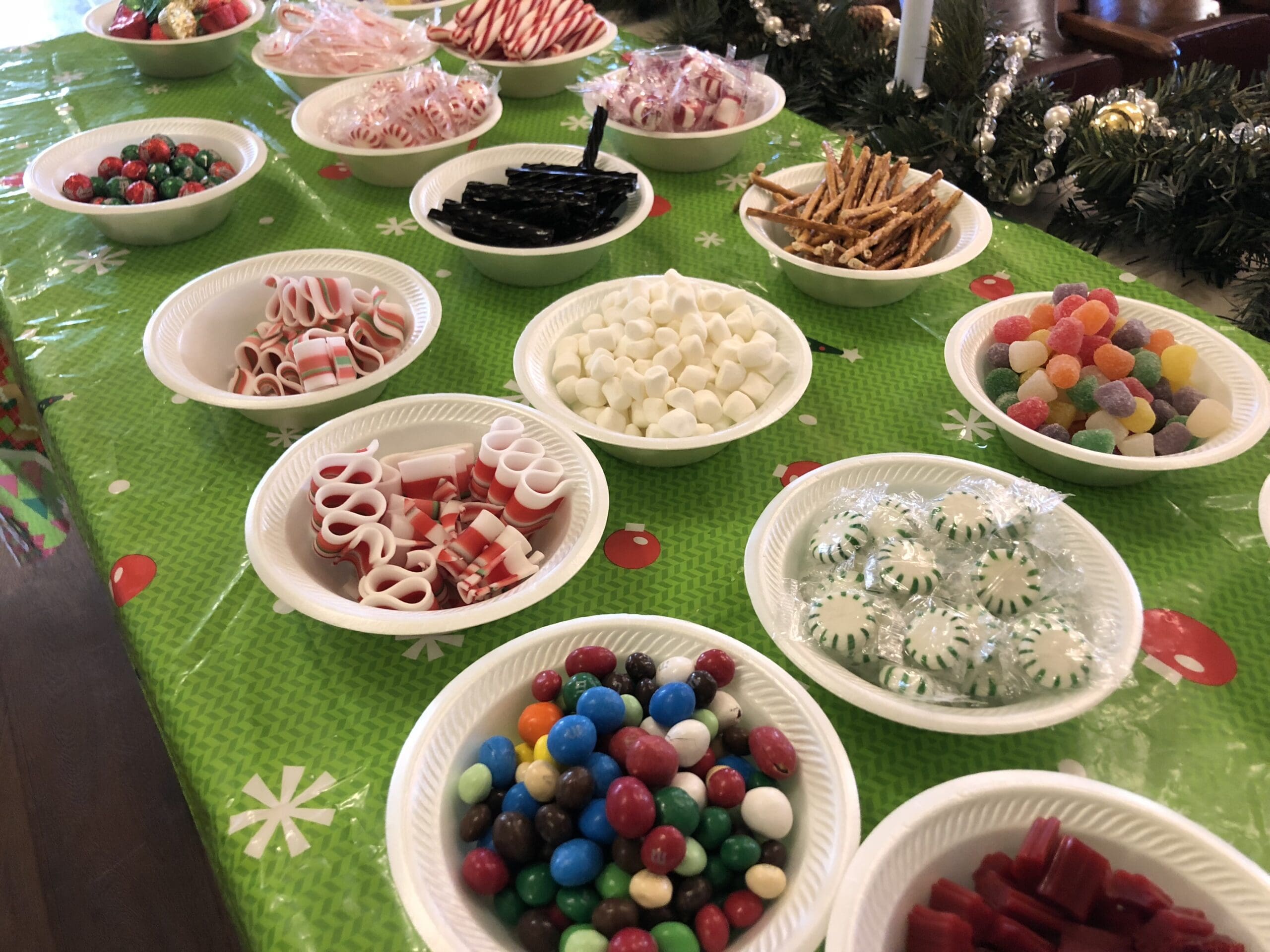 A variety of candies displayed on paper plates on a festive tablecloth at Heritage Square, Oxnard, including gummy candies, marshmallows, and licorice.