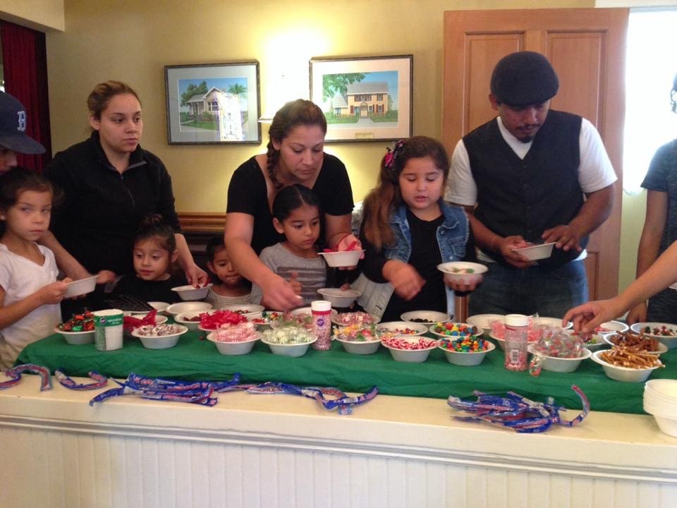 A group of adults and children serving themselves at a dessert buffet with various sweets and toppings at Heritage Square.